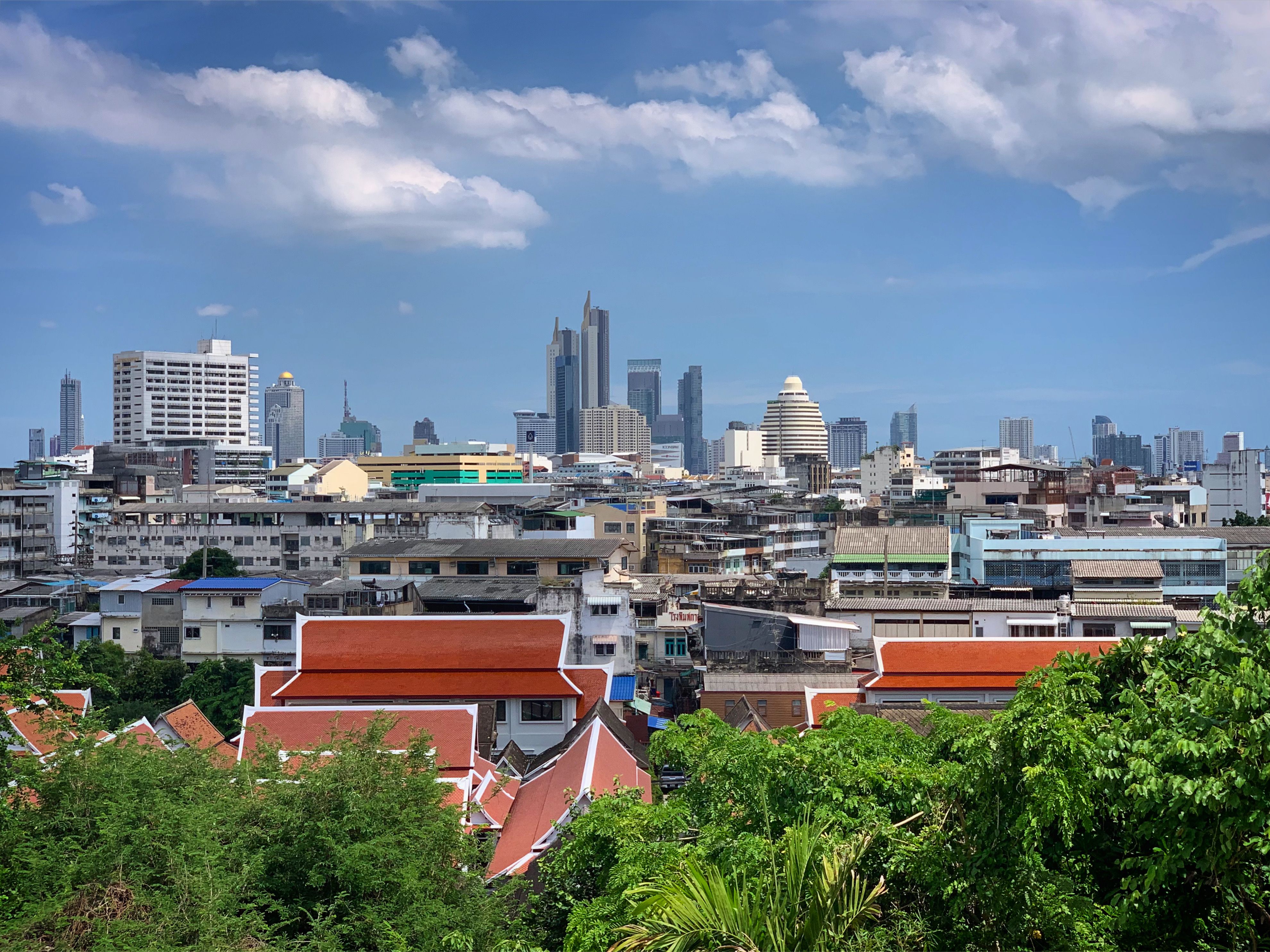 Bangkok's modern skyline rising above traditional Thai rooftops