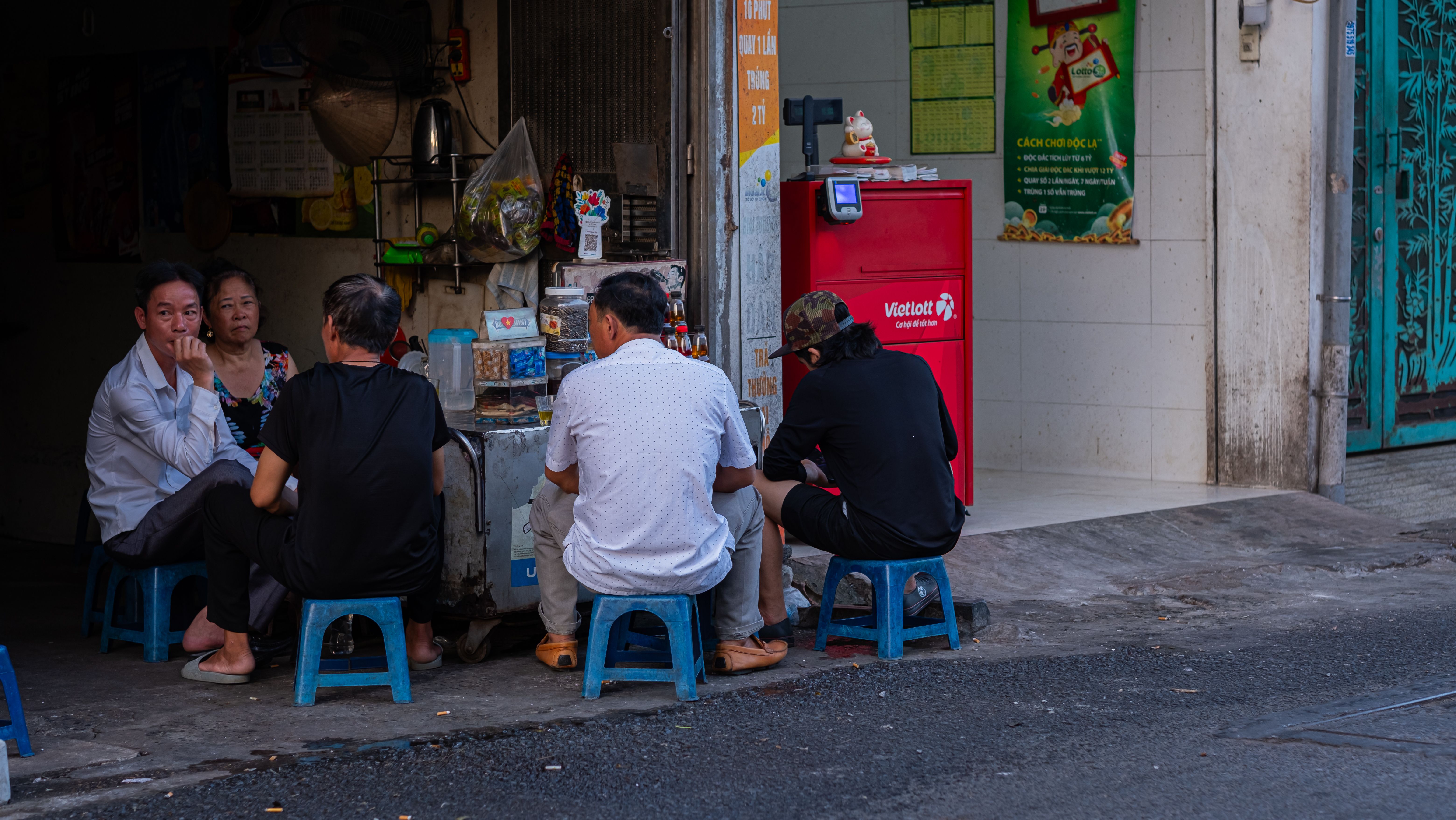 Group of adults in conversation outside a small shop in Hanoi, Vietnam