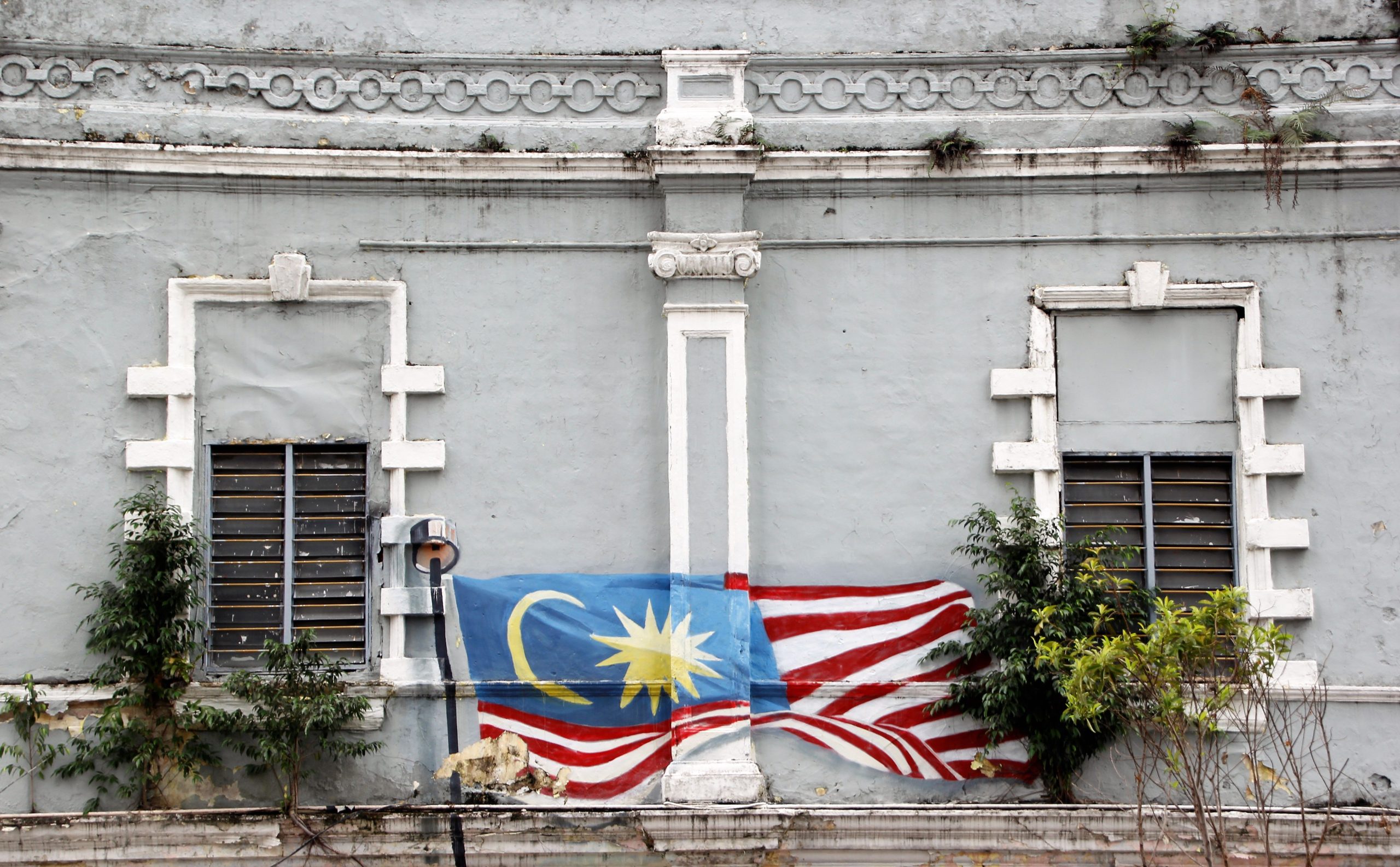 Artistic mural of the Malaysian flag on a historic building facade in Kuala Lumpur