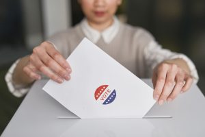 Person casting a ballot into a ballot box during an election