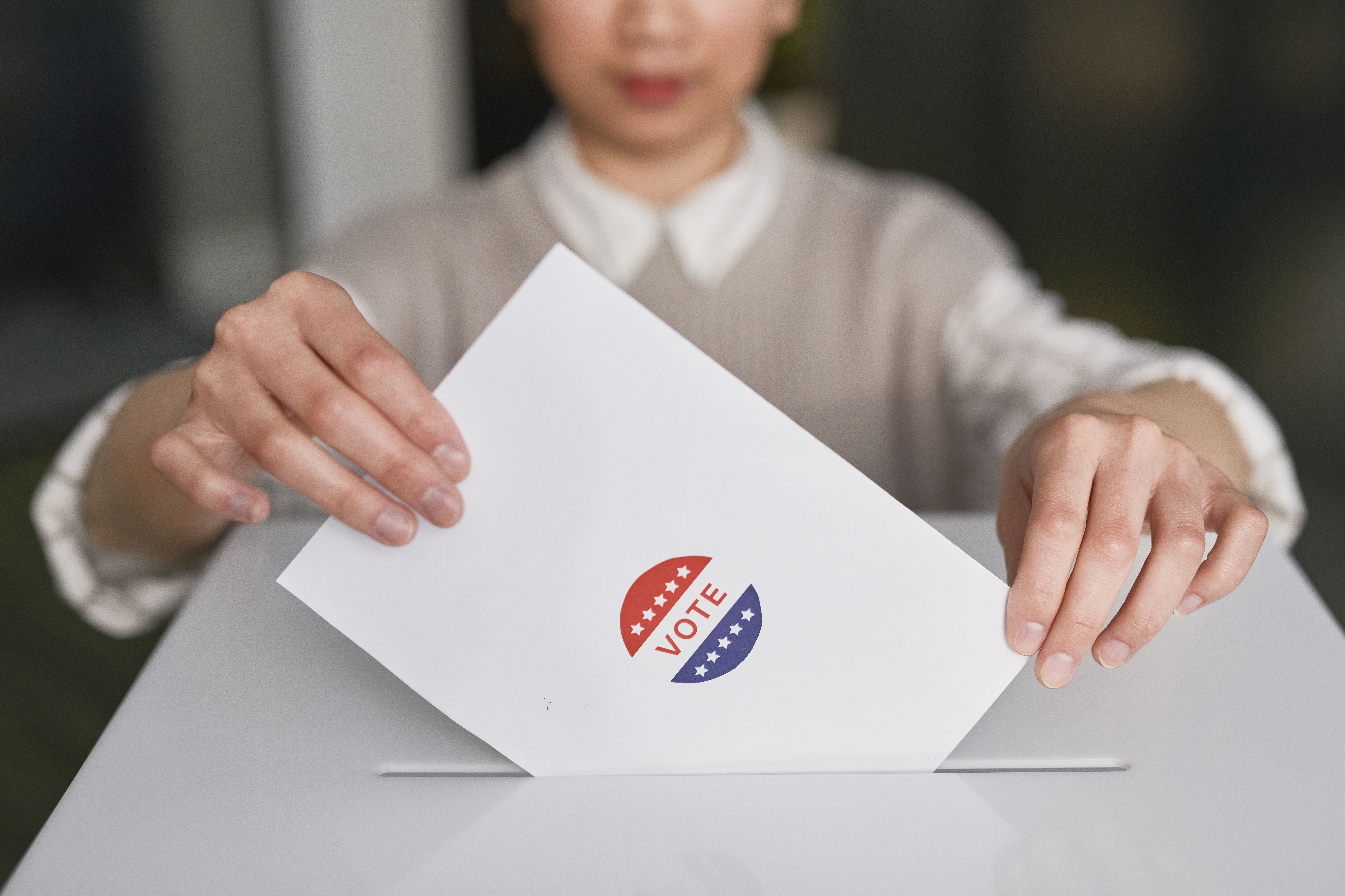 Person casting a ballot into a ballot box during an election